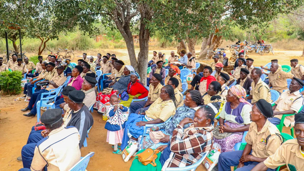 Hundreds of older persons seated together under acacia trees at a Thayu Life Foundation community gathering.