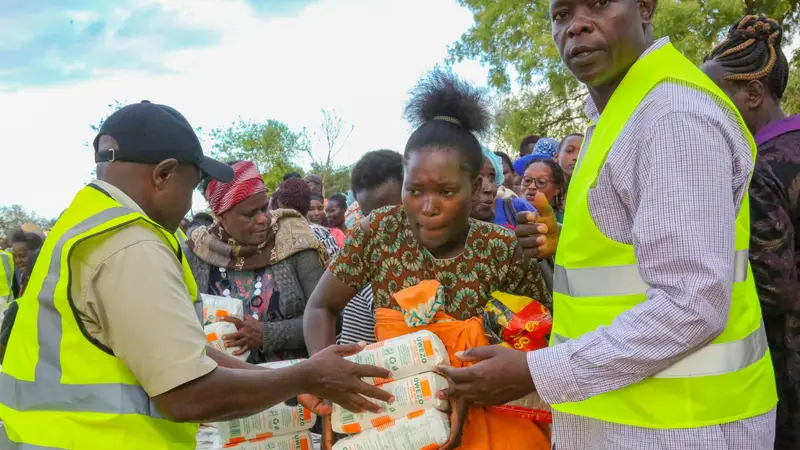 A Thayu Life Foundation volunteer handing a package of maize flour to a woman at a community distribution.